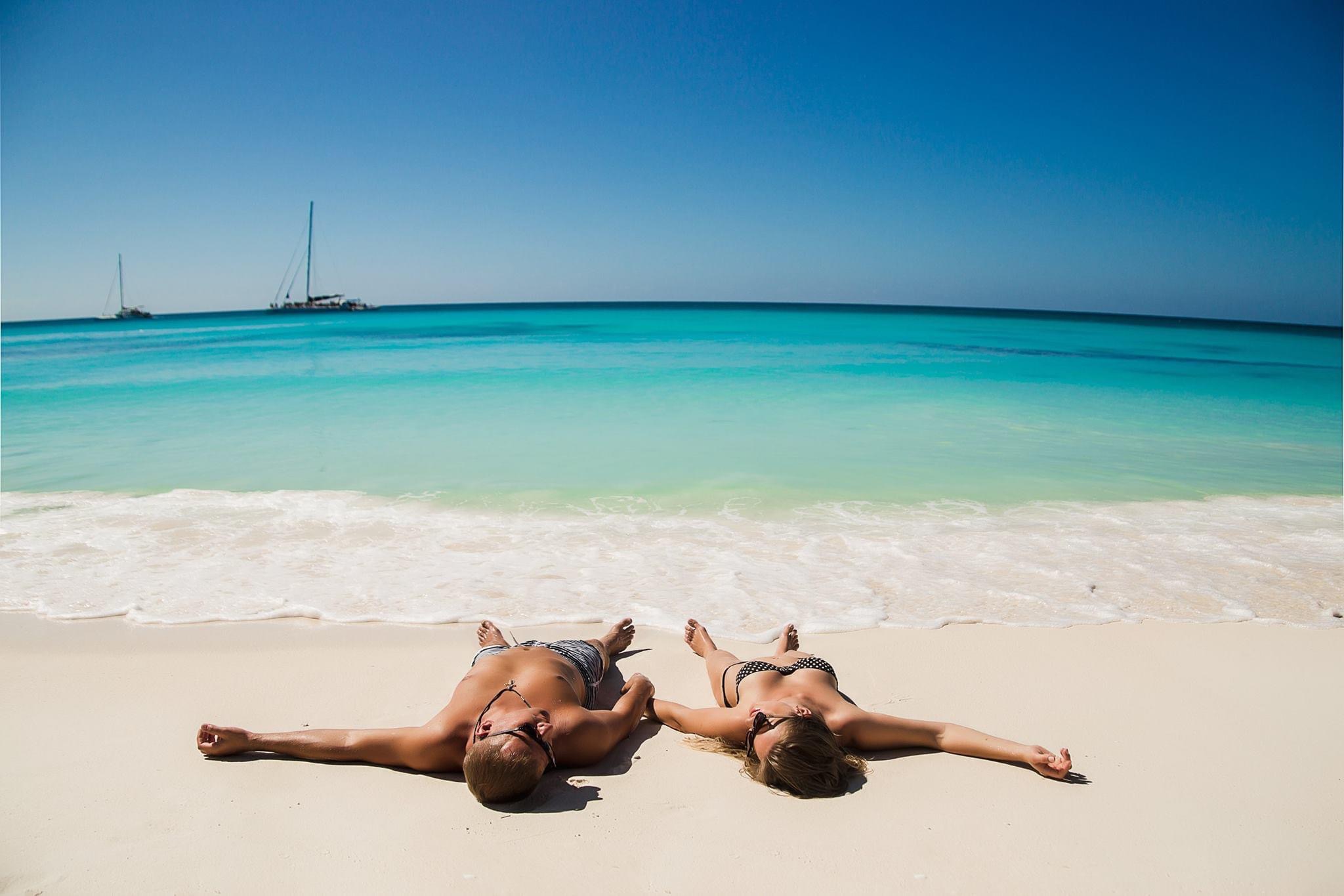 Visitantes descansan en una playa de arena blanca junto al mar Caribe