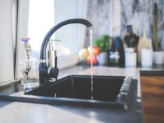 Agua corriente de un grifo hacia un fregadero; fotografía de archivo de 2015