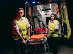Personal de emergencias prepara una camilla junto a una ambulancia, imagen de archivo