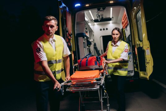 Personal de emergencias prepara una camilla junto a una ambulancia, imagen de archivo