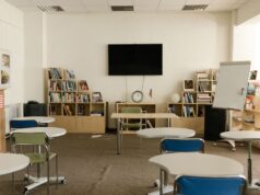 Suspenden clases este martes en planteles vulnerables bajo alerta amarilla Aula vacía con mesas, sillas y pizarra; fotografía de archivo de 2021 alusiva a la suspensión de clases.