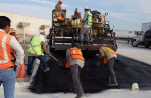 Trabajadores colocan asfalto durante labores de reparación vial; imagen ilustrativa