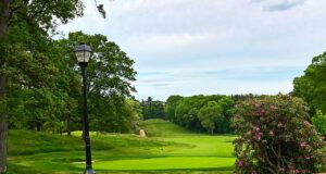 Vista del campo Bethpage Green, con green, bandera y árboles alrededor, en Nueva York.