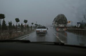 Vehículos circulando por una carretera mojada bajo la lluvia; fotografía de archivo de 2021.