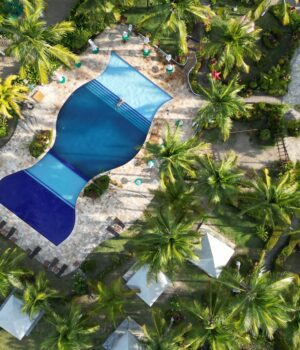 Vista aérea ilustrativa de un complejo turístico con piscina y palmeras en Punta Cana