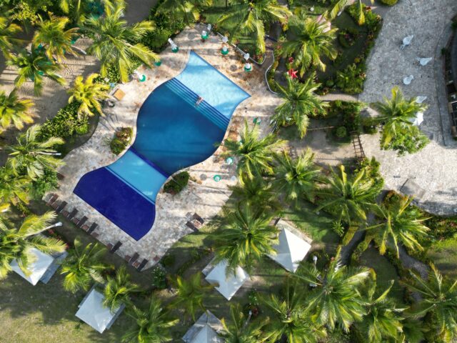 Vista aérea ilustrativa de un complejo turístico con piscina y palmeras en Punta Cana