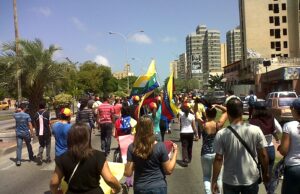 Manifestantes sostienen banderas venezolanas durante una concentración pública