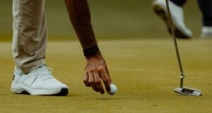 Golfista coloca una bola sobre el green durante una sesión de golf.