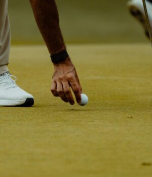 Golfista coloca una bola sobre el green durante una sesión de golf.