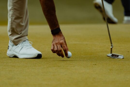 Golfista coloca una bola sobre el green durante una sesión de golf.