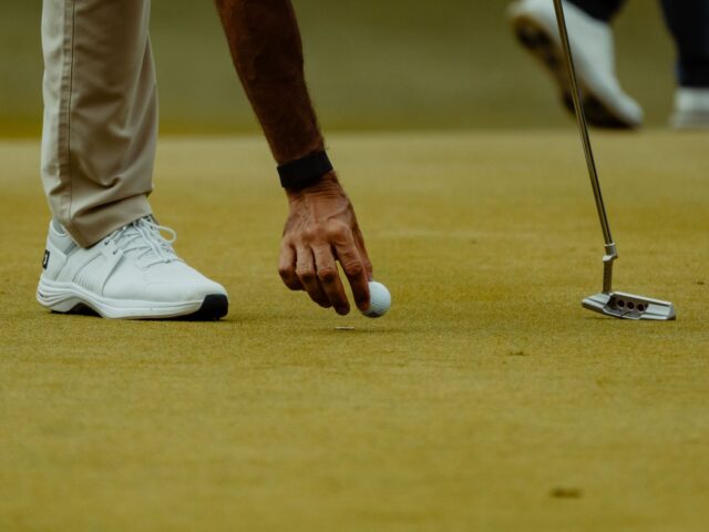 Golfista coloca una bola sobre el green durante una sesión de golf.