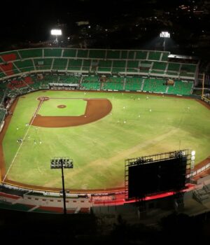 Estadio de béisbol iluminado durante un juego nocturno, imagen ilustrativa