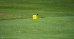 Bandera amarilla y pelotas sobre el green de un campo de golf