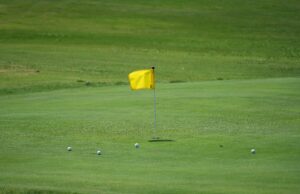 Bandera amarilla y pelotas sobre el green de un campo de golf