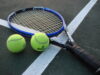 Raqueta y pelotas de tenis sobre una cancha, fotografía de archivo.
