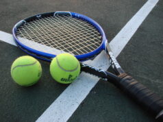 Raqueta y pelotas de tenis sobre una cancha, fotografía de archivo.