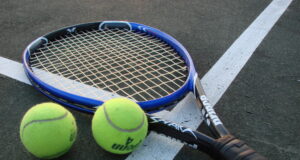 Raqueta y pelotas de tenis sobre una cancha, fotografía de archivo.