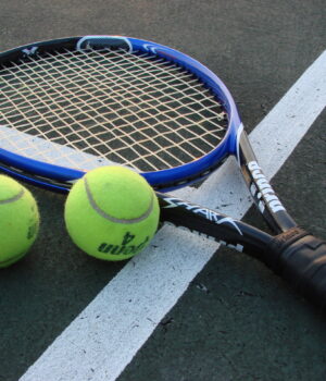 Raqueta y pelotas de tenis sobre una cancha, fotografía de archivo.