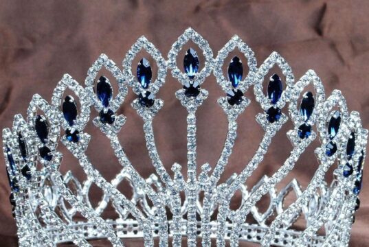 Tiara circular con pedrería azul usada como imagen ilustrativa de un certamen de belleza