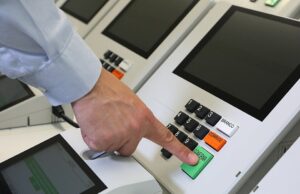 Una mano presiona el botón de confirmación de una urna electrónica brasileña; fotografía de archivo de 2021.